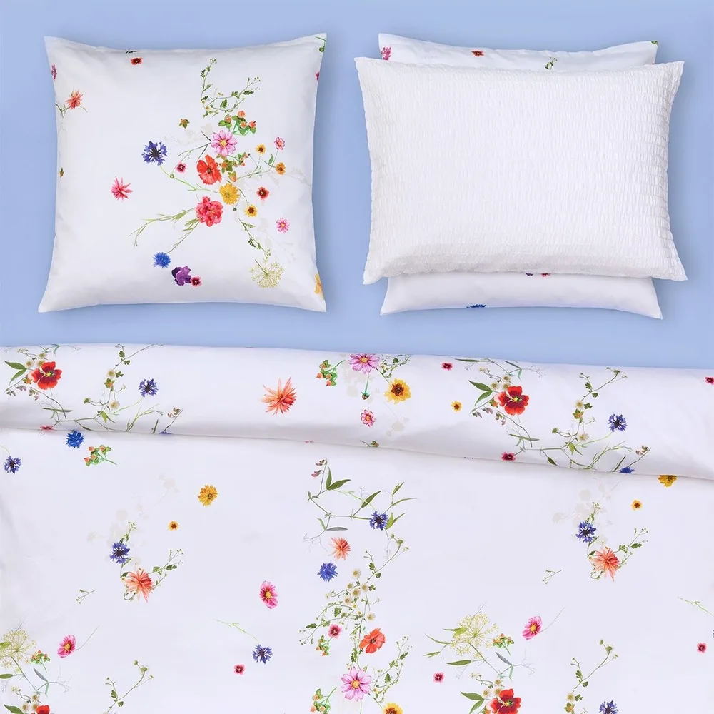 Un lit avec une couette à motifs floraux et des oreillers dessus