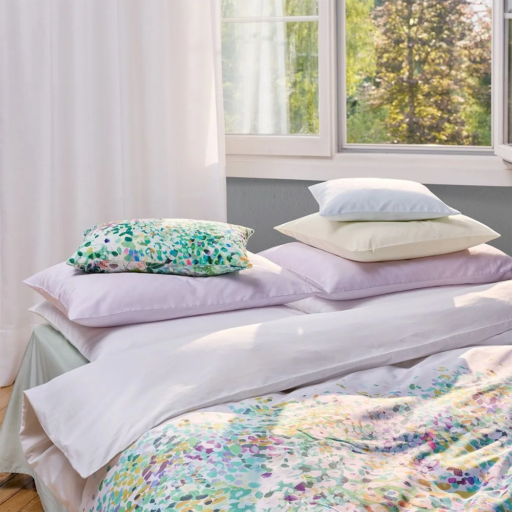 Un lit avec une couette à motifs floraux et des oreillers dessus