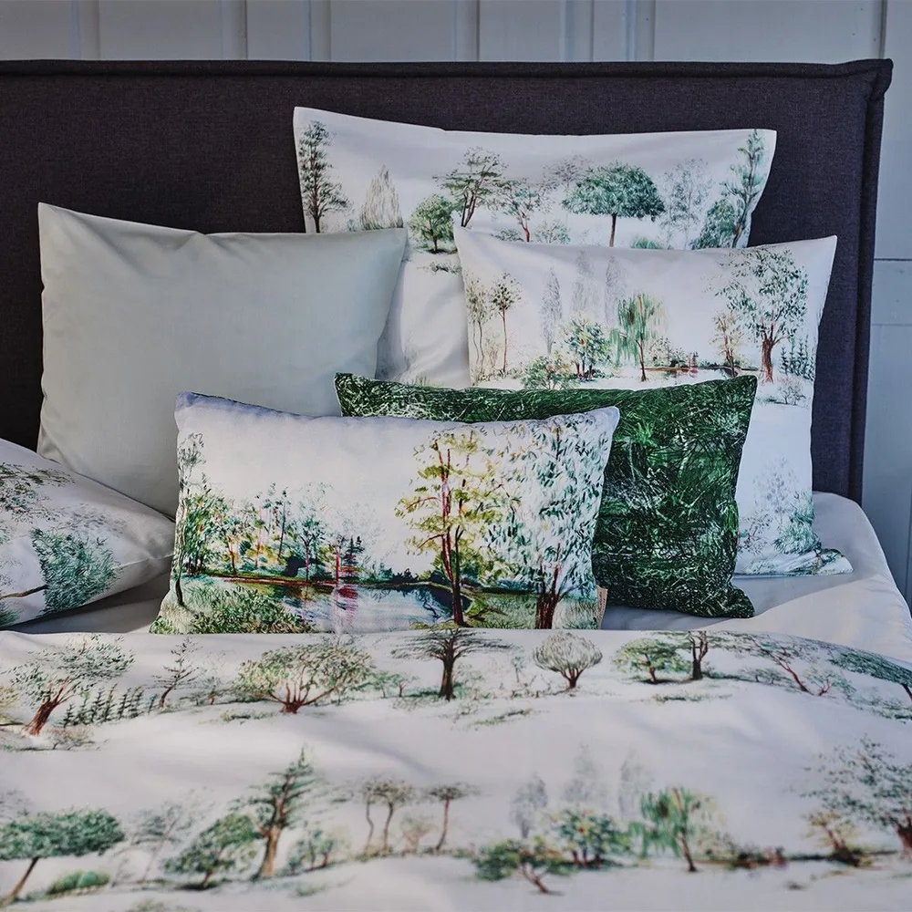 Un lit avec beaucoup d'oreillers et une couverture avec des arbres dessus