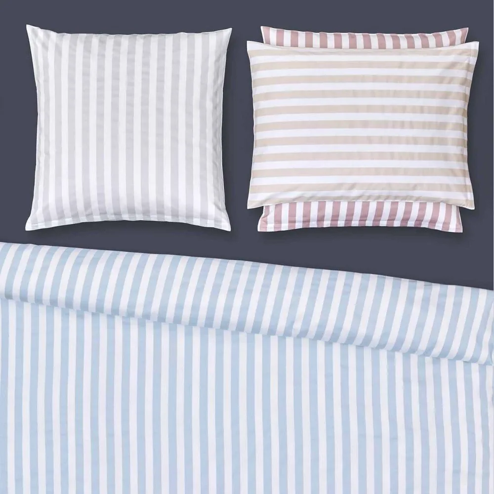 A bed with striped sheets and pillows on it
