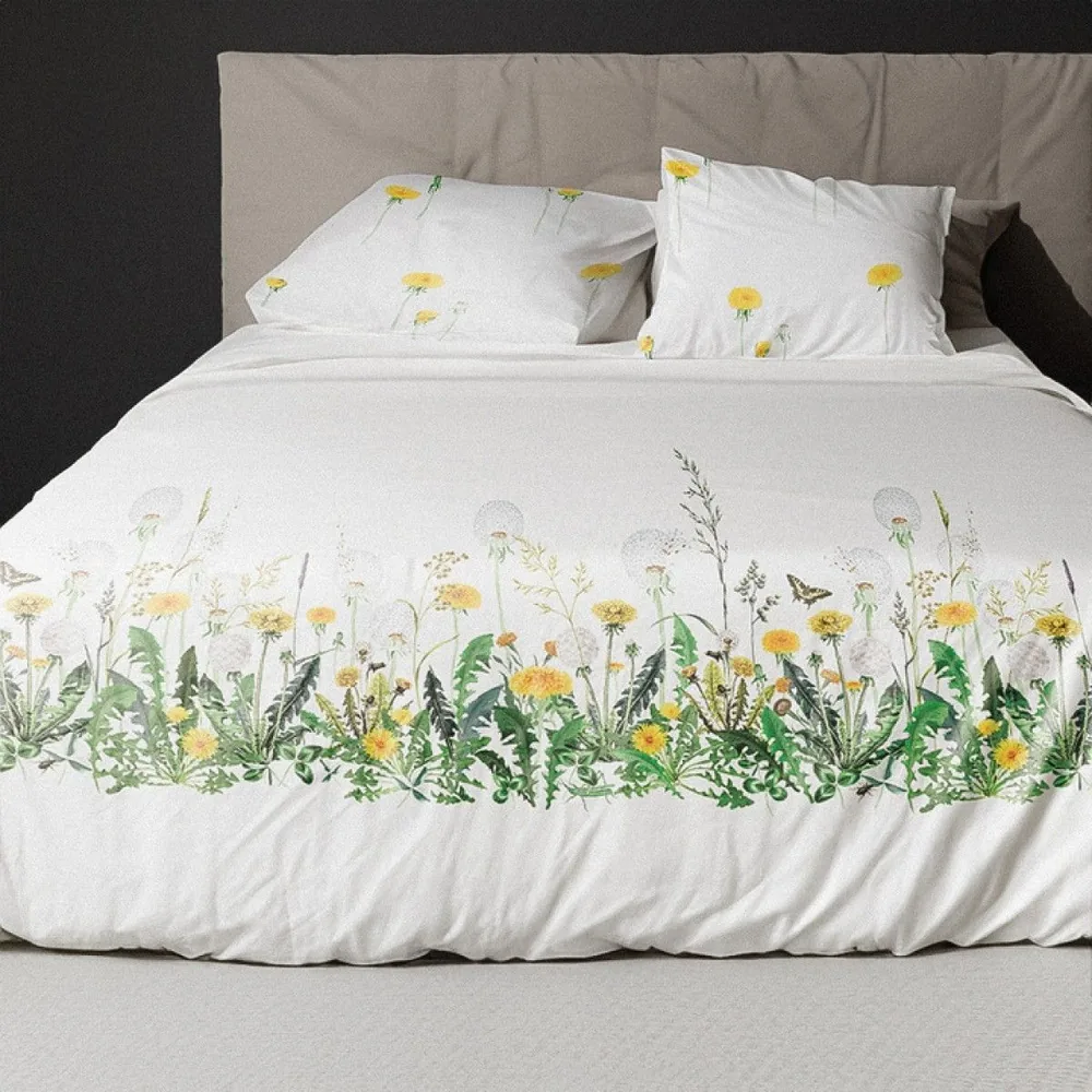 A bed with a white comforter with yellow flowers on it