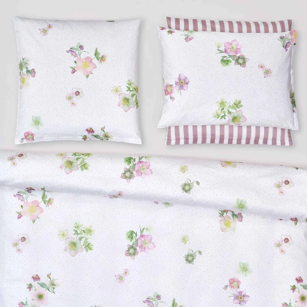 A bed with a floral comforter and pillows on it