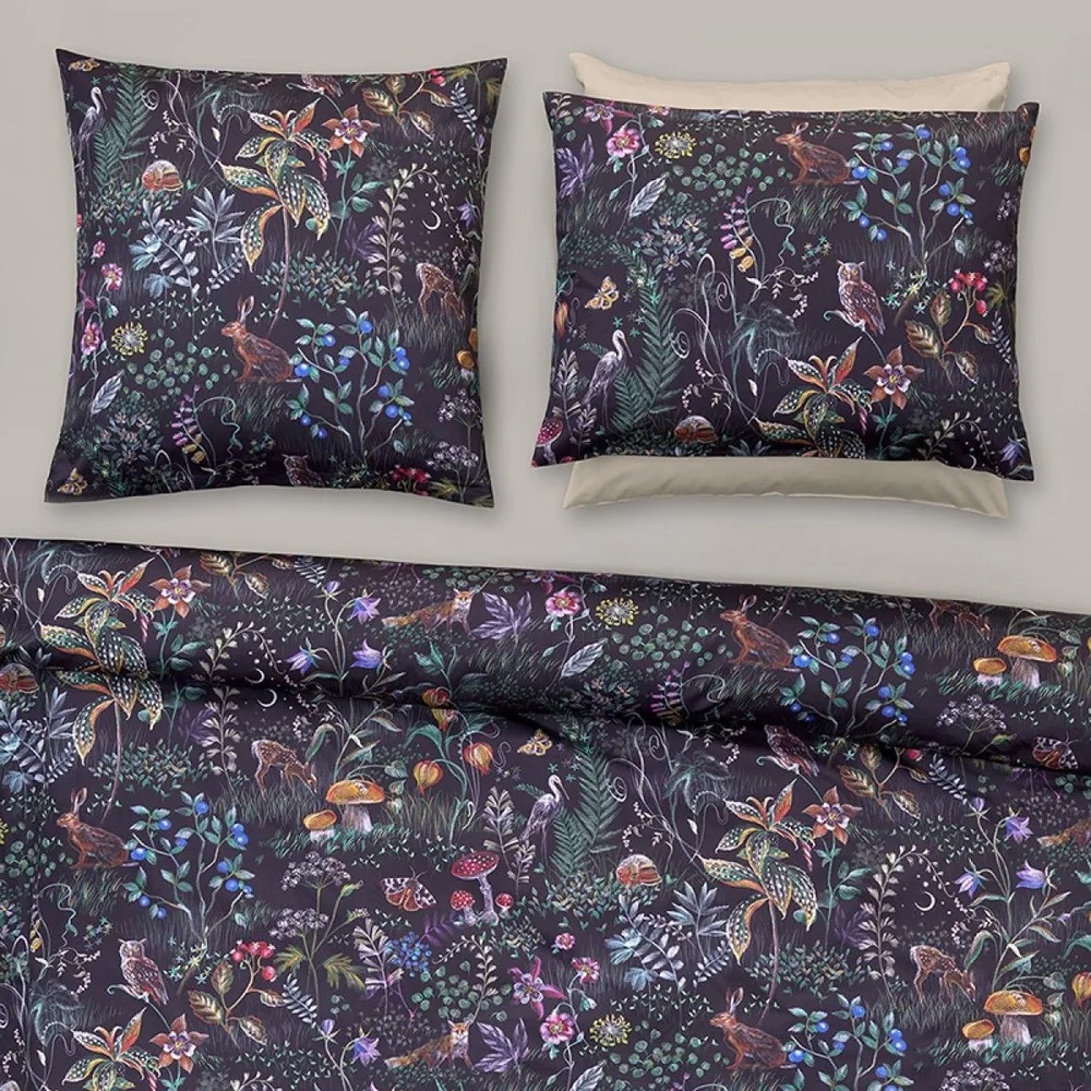 A bed with a duvet cover and two pillows with a floral pattern on them.