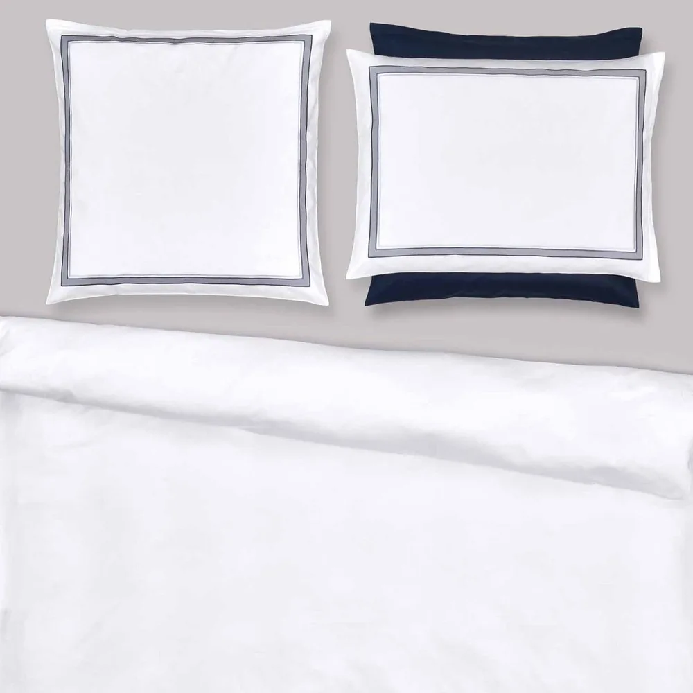 Two pillows are sitting on top of a bed with a white comforter.