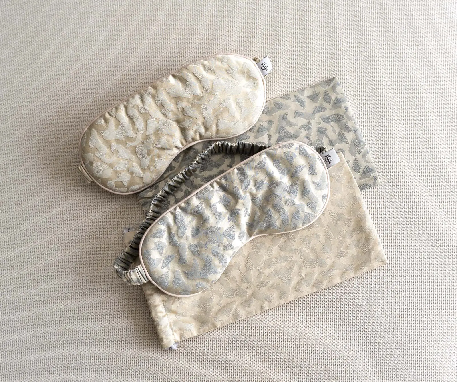 Zwei Schlafmasken aus Seide von Christian Fischbacher mit passenden Beuteln in Creme und Silbergrau